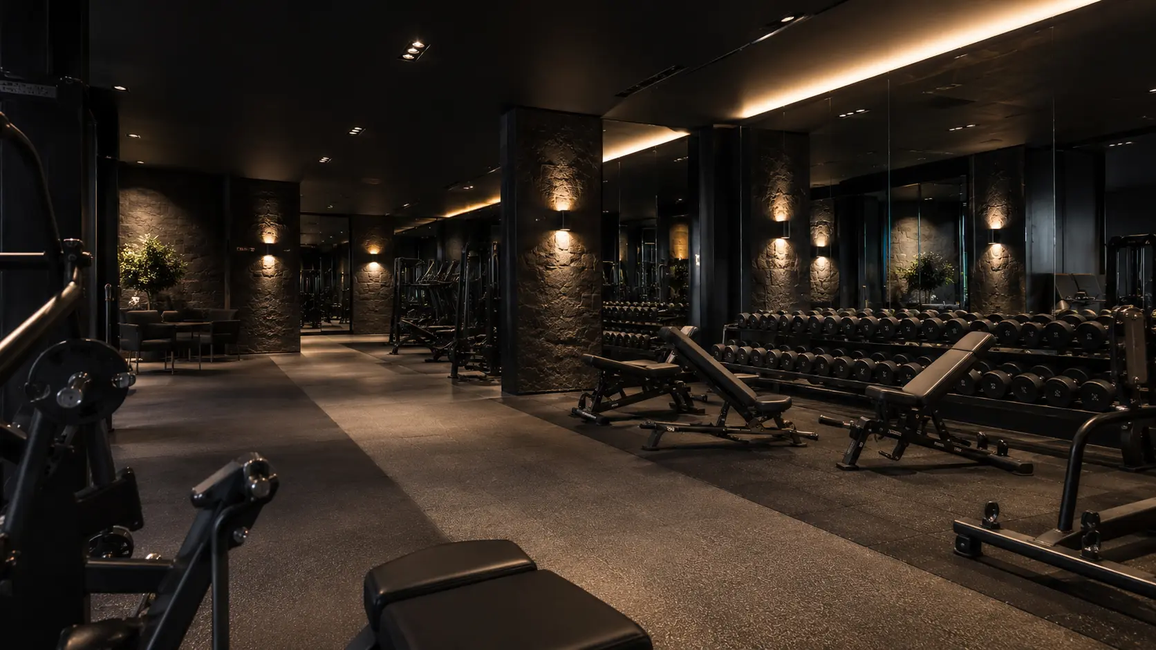 Low-lit private training floor with dumbbells and benches